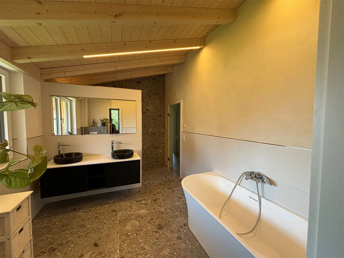 Badezimmer im Neubau mit Lehmputzwänden, freistehender Badewanne und Holzdecke